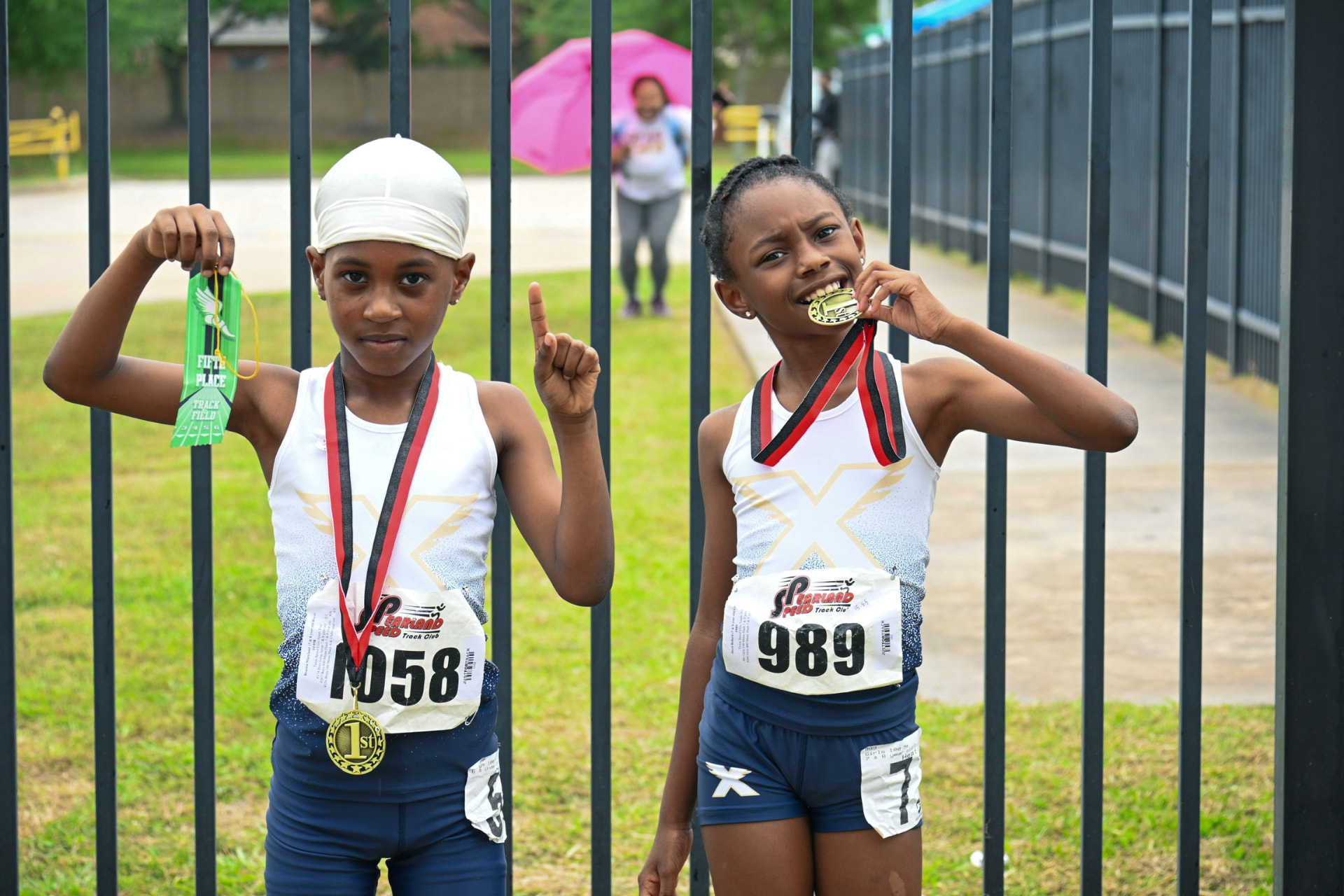 Two young TSE athletes showing off a first place medal and a fifth place ribbon