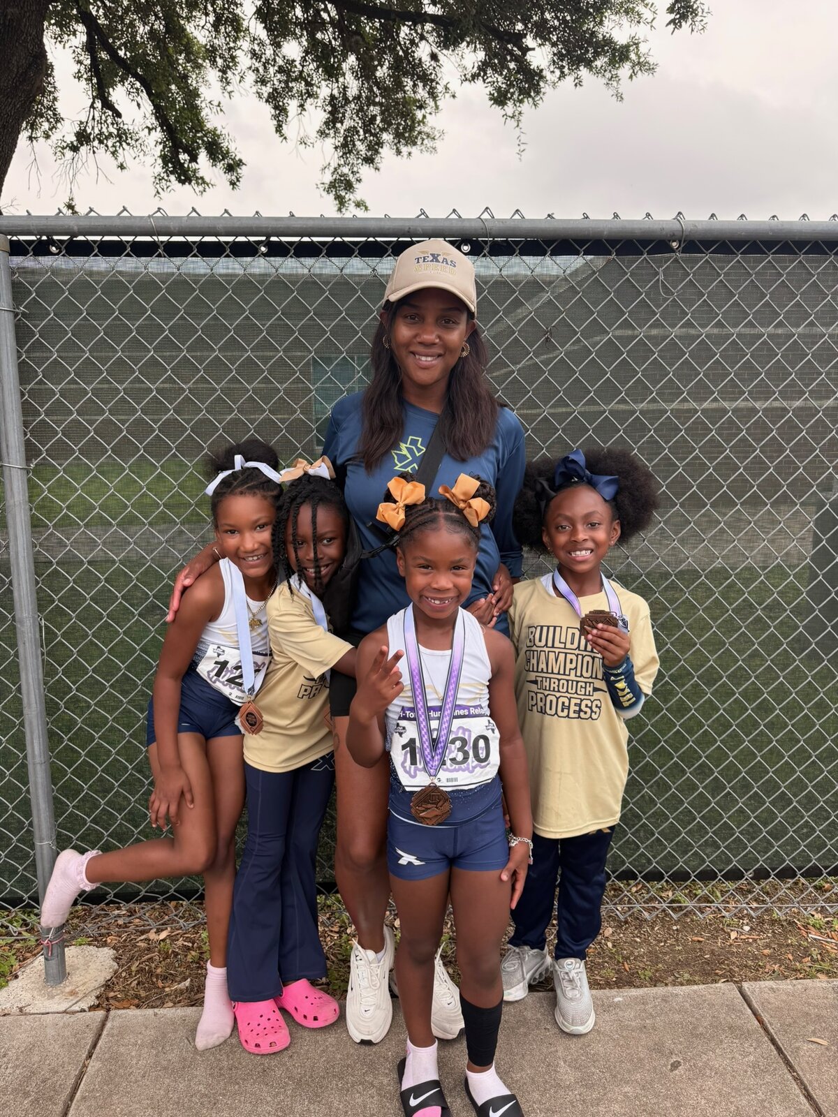 Coach with four young athletes wearing medals at a meet